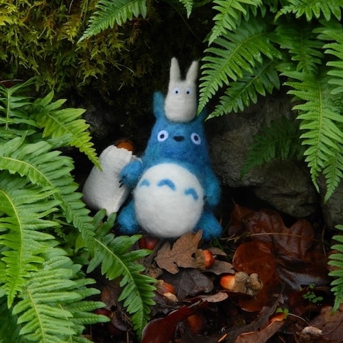 A needle-felted Totoro and Chii-Totoro amidst acorns, oak leaves, & ferns